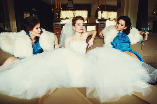 Bride and bridesmaids look cool posing on the big beig couch