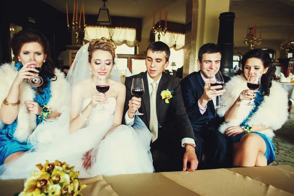 Newlyweds and friends drink wine sitting on the couch