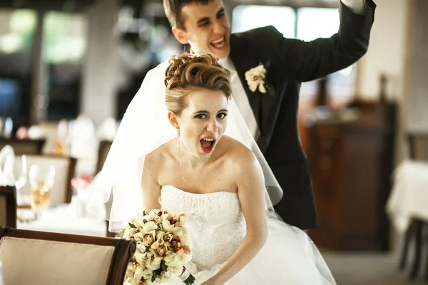 Bride looks sexy while laughing groom stands behind her — Stock Photo, Image