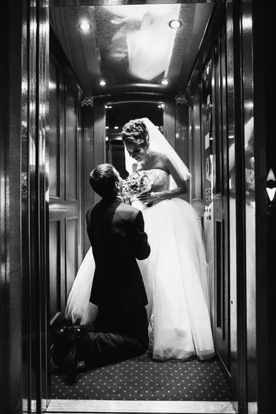 新郎站在新娘在电梯前的膝盖上 — 图库照片