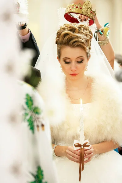 Braut blickt auf eine Kerze, während Brautjungfer eine Hochzeitskrone in der Hand hält — Stockfoto