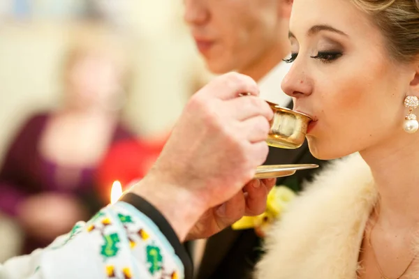 Braut empfängt heilige Kommunion aus den Händen des Priesters während einer Hochzeit — Stockfoto