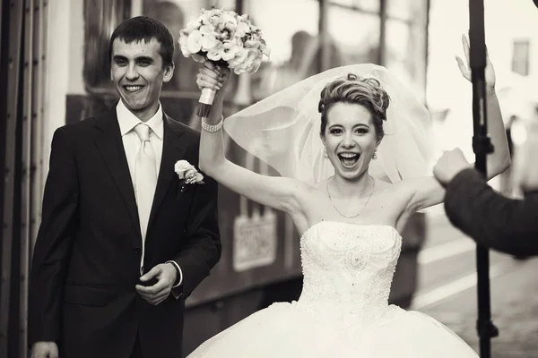 Braut hebt die Hände und lächelt beim Gehen mit einem Bräutigam — Stockfoto