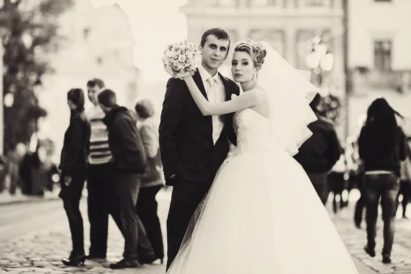 Stunning just married couple pose on the square full of people — Stock Photo, Image