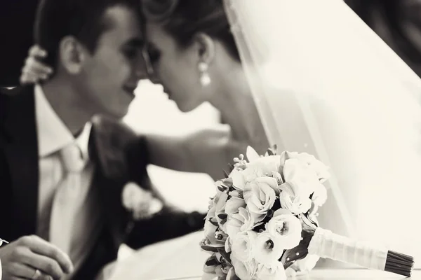 Wedding bouquet lies on the table before peacefull newlyweds — Stock Photo, Image