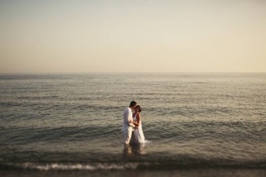 Sakin gelin ve damat deniz suda ayakta orada sarılmak