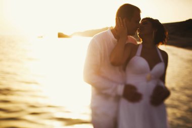 Deniz suyu ayakta mutlu bir yeni evliler arkasında günbatımı parlar