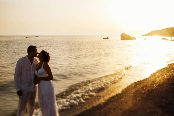 Sposa si appoggia ad uno sposo in piedi sulla riva del mare luminoso mentre su — Foto Stock