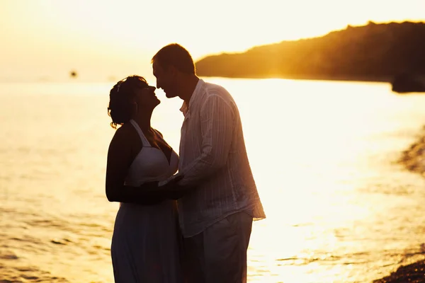 Novio abrazarse firmemente de pie en la orilla del mar en el l — Foto de Stock