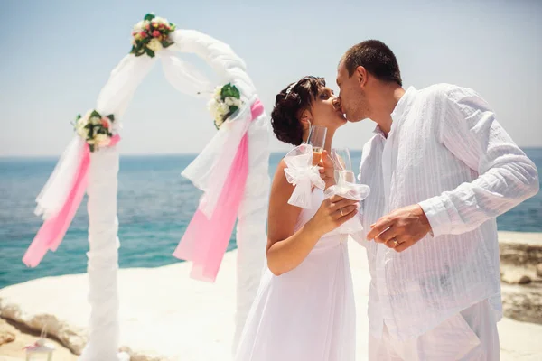 Novia y novio beso de pie detrás de un altar de bodas con champa — Foto de Stock