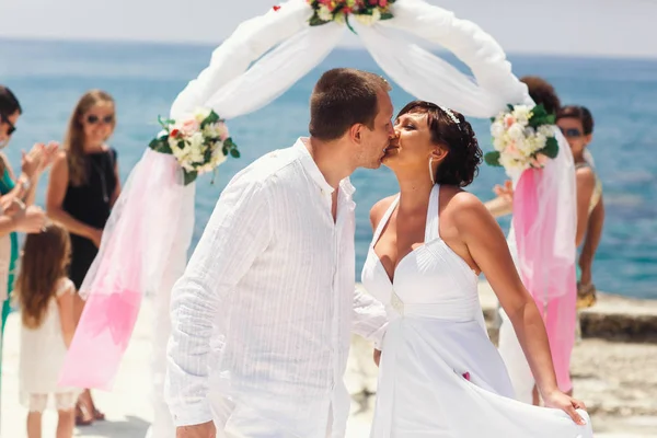 Novio en camisa blanca kises novia tierna de pie junto al mar —  Fotos de Stock