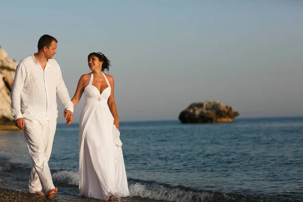 Pareja de boda bronceada camina a lo largo del mar azul tranquilo — Foto de Stock