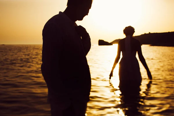 Man kijkt naar een bruid terwijl ze daalt in het zeewater geconfronteerd met t — Stockfoto