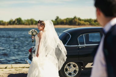 Güneşli bir günde Haliç üzerinde eski bir araba arkasında gelin pozlar