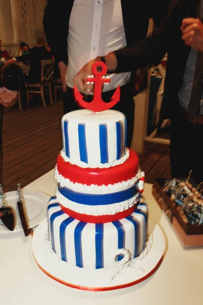 Смачний весільний торт, прикрашений синіми смугами з червоним якорем — стокове фото
