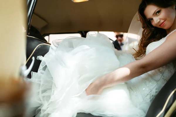 A look through the open door on a pretty bride inside the car — Stock Photo, Image