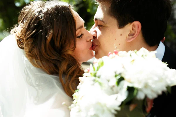 Mooie bruidspaar kus staande buiten — Stockfoto