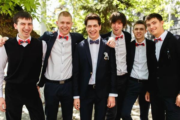 Smiling groom and groomsmen pose outside