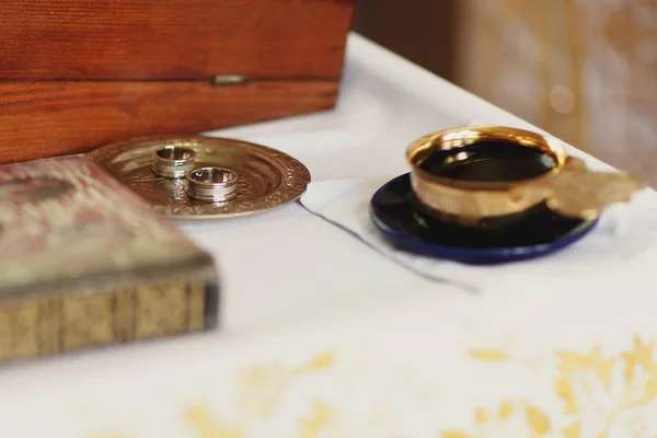 Snubní prsteny leží na malou stříbrnou deskou za staré Bible — Stock fotografie