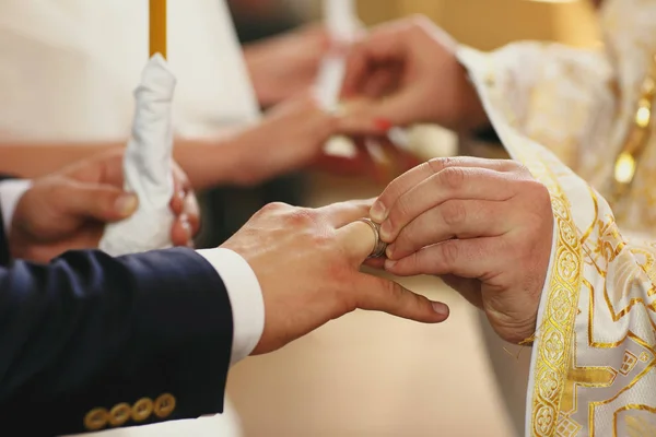 Sacerdote coloca anéis de casamento em recém-casados dedos — Fotografia de Stock