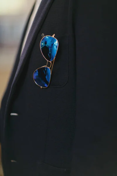 Gafas de sol azules cuelgan del bolsillo de una chaqueta —  Fotos de Stock