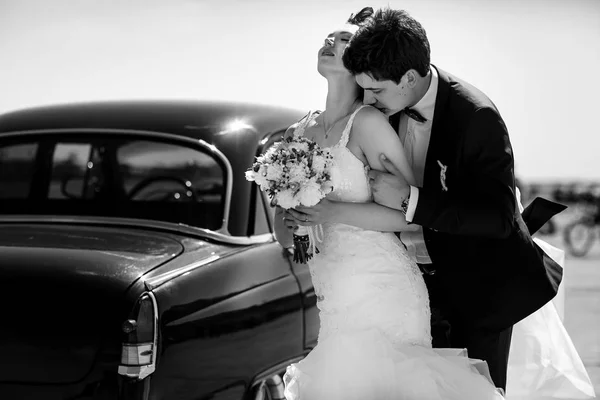 Sposa si appoggia a uno sposo mentre le bacia la spalla in piedi und — Foto Stock