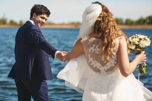 Sposo guarda una sposa sopra la sua spalla tenendo la mano stretta — Foto Stock