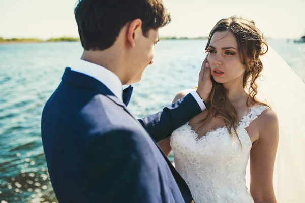 Braut sieht Bräutigam verführerisch am Meer posierend an — Stockfoto