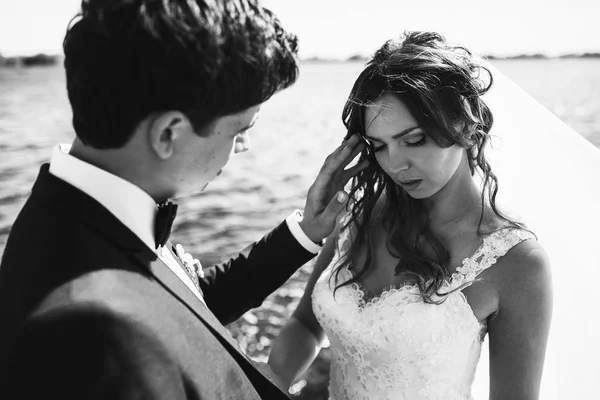 Sposo regola i capelli della sposa toccandole teneramente il viso — Foto Stock