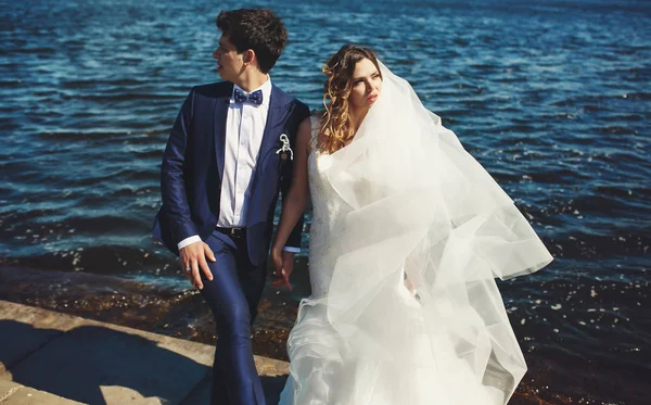 Novia y novio se ven de diferentes maneras posando junto al mar —  Fotos de Stock