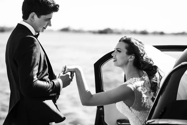 Жених помогает красивой невесте выйти из старой машины — стоковое фото