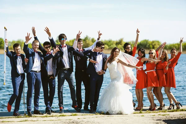 Les jeunes mariés posent avec des amis sur la rive de l'estuaire — Photo