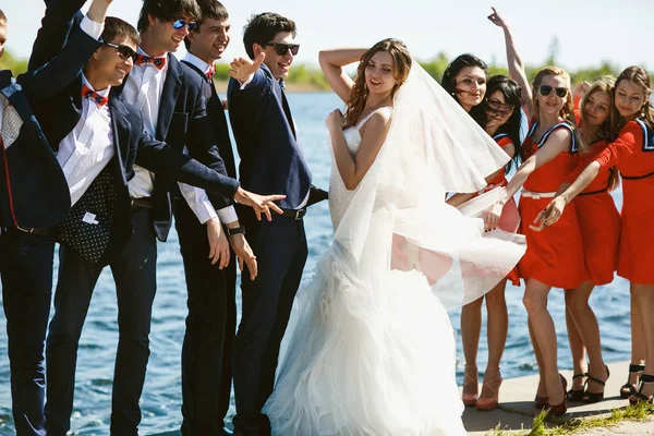 Recém-casados e amigos dançam posando na costa do mar — Fotografia de Stock