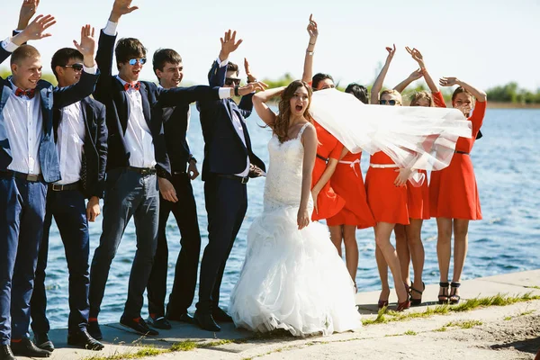 Le vent souffle le voile de la mariée sur les demoiselles d'honneur pendant qu'elles se tiennent debout — Photo