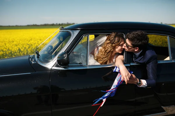 Groom embrasse le nez de la mariée en l'atteignant par le vent de la voiture — Photo