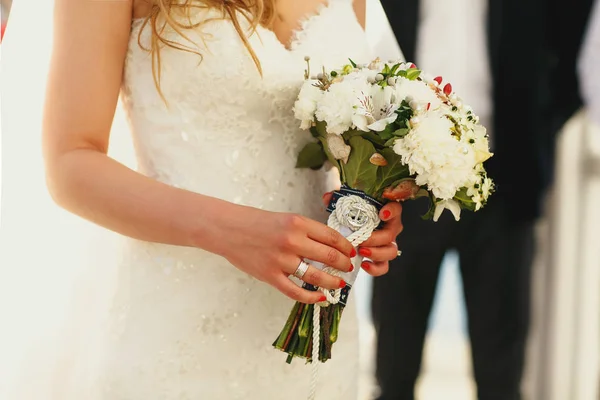 Noiva segura em suas mãos ternas um buquê de casamento decorado com — Fotografia de Stock