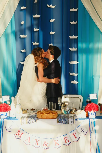 Um beijo apaixonado de recém-casados em pé à mesa de jantar — Fotografia de Stock