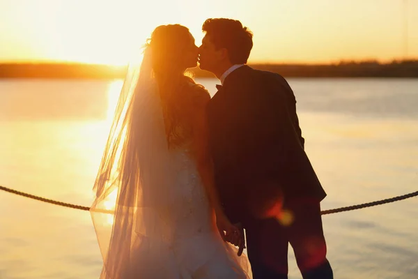 Bräutigam küsst Braut zärtlich die Lippen, die am Ufer steht — Stockfoto