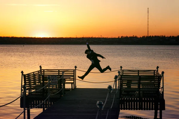 Gelukkig man springt op de brug aan de oever van een estuarium — Stockfoto
