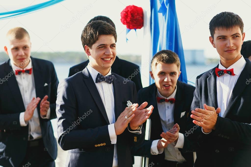 Groom and groomsmen wait for a bride behind a wedding altar