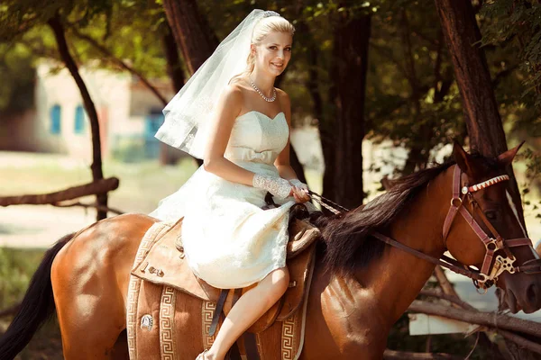Αστεία νύφη στο νυφικό φόρεμα βόλτες ένα άλογο — Φωτογραφία Αρχείου