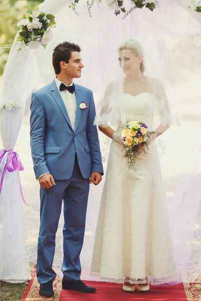 Noiva e um noivo ao lado do arco de casamento — Fotografia de Stock