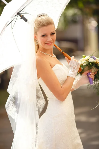 Nevěsta s deštníkem a svatební kytice — Stock fotografie
