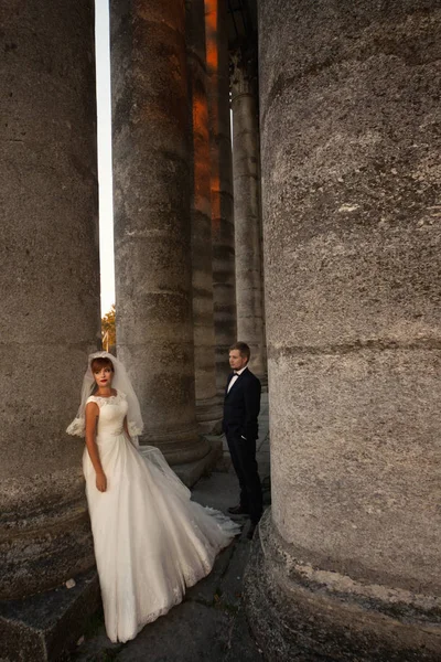 O belo casal apaixonado fica perto de coloums — Fotografia de Stock