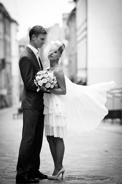 Groom admires a thoughtful stylish bride standing on the street