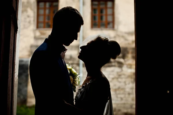 Silhouettes of newlyweds standing on the old courtyard — Stock Photo, Image