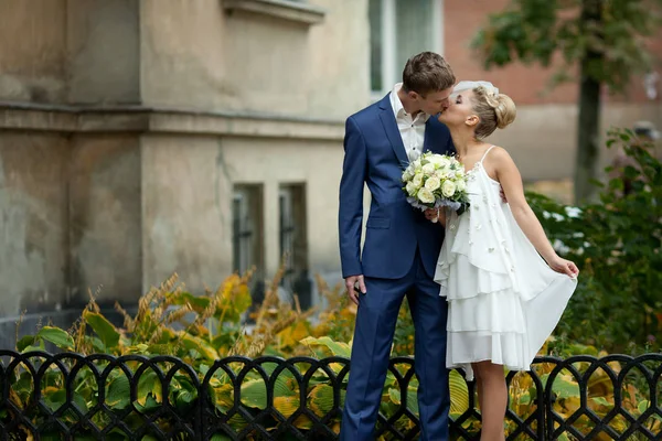 Novio en traje azul besa a una novia en vestido blanco corto — Foto de Stock