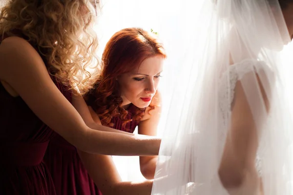 Družička pomáhá nosit svatební šaty — Stock fotografie