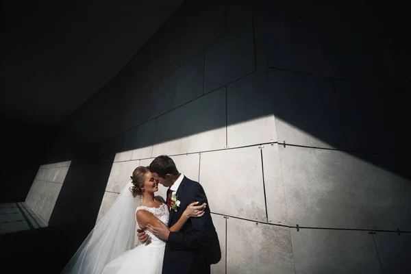 O belo casal apaixonado fica perto da parede — Fotografia de Stock