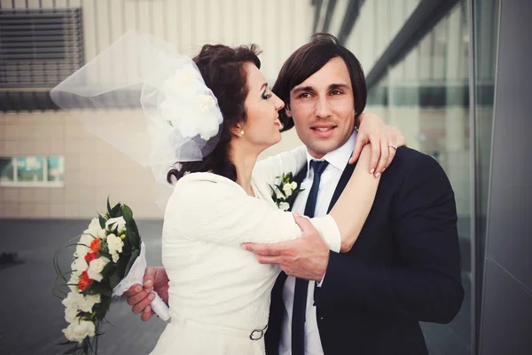 Όμορφος groom κατέχει μια γαμήλια ανθοδέσμη, ενώ η νύφη προσπαθεί να φιλήσει — Φωτογραφία Αρχείου